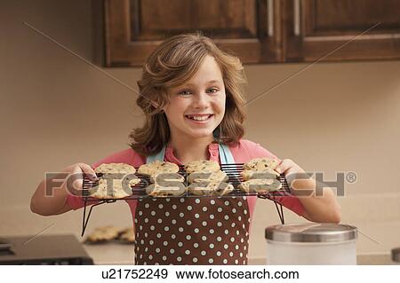 Portrait of girl (10-11) holding biscuits in kitchen View Large Photo Image Stock Photo - Portrait of girl (10-11) holding biscuits in kitchen. Fotosearch
