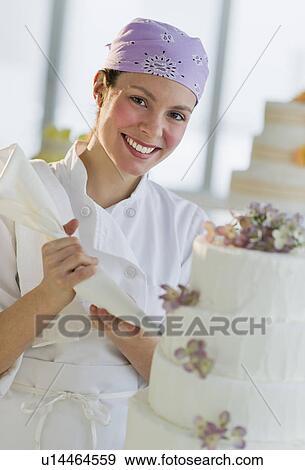 Portrait of happy young woman decorating wedding cake View Large Photo Image Stock Photo - Portrait of happy young woman decorating wedding cake. Fotosearch
