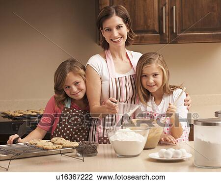 Stock Image - Portrait of mother baking with daughters (10-11) in kitchen. Fotosearch