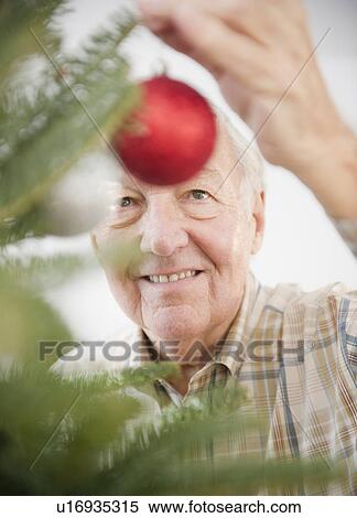 Stock Photography - Portrait of senior man decorating Christmas tree. Fotosearch