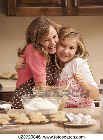 Stock Photograph - Portrait of two girls (10-11) baking in kitchen. Fotosearch