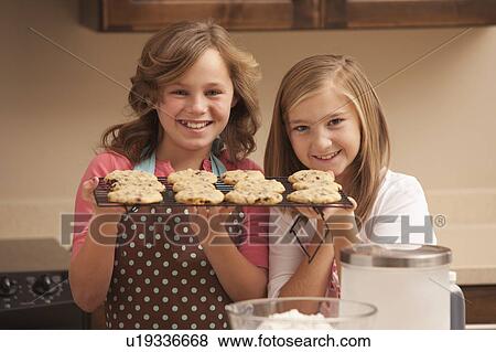 Portrait of two girls (10-11) holding biscuits in kitchen View Large Photo Image Stock Photo - Portrait of two girls (10-11) holding biscuits in kitchen. Fotosearch