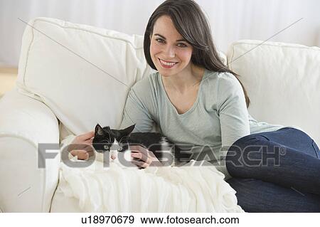 Stock Photo - Portrait of woman with cat on sofa. Fotosearch
