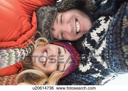 Portrait of young couple lying in snow View Large Photo Image Stock Photograph - Portrait of young couple lying in snow. Fotosearch