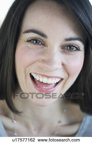 Stock Image - Portrait of young laughing woman, studio shot. Fotosearch