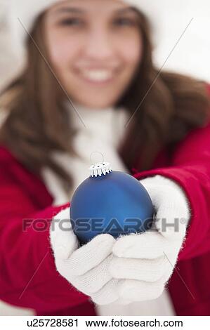 Portrait of young woman holding Christmas bauble outdoors View Large Photo Image Stock Image - Portrait of young woman holding Christmas bauble outdoors. Fotosearch