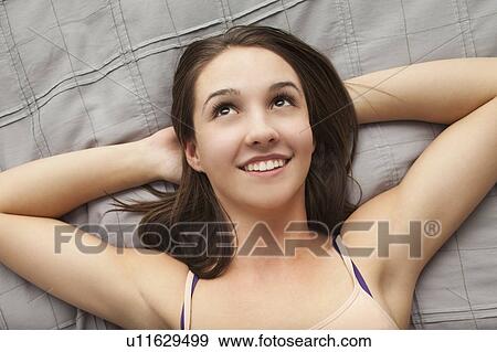 Portrait of young woman lying on bed View Large Photo Image Stock Photo - Portrait of young woman lying on bed. Fotosearch