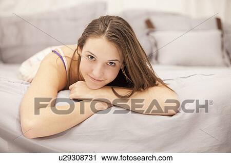 Portrait of young woman relaxing on bed View Large Photo Image Stock Image - Portrait of young woman relaxing on bed. Fotosearch