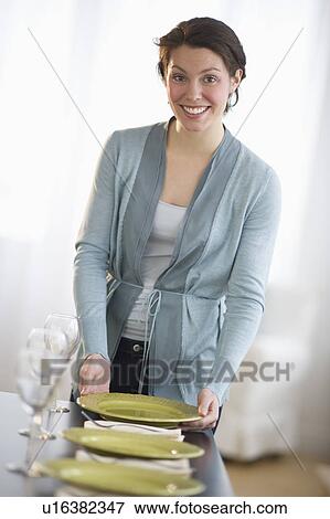 Stock Photo - Portrait of young woman setting table. Fotosearch