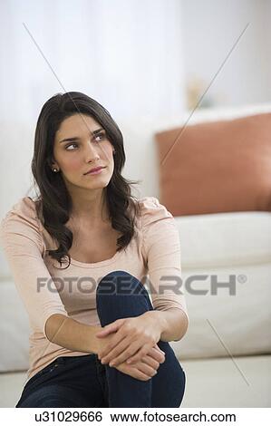 Stock Photograph - Portrait of young woman sitting on floor. Fotosearch