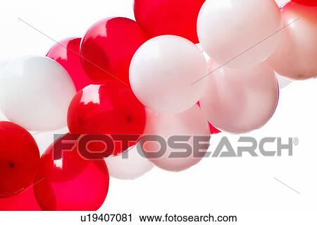 Stock Image - Red and white balloons on white background, studio shot. Fotosearch