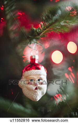 Stock Photograph - Santa Claus Christmas decoration hanging on Christmas tree, studio shot. Fotosearch