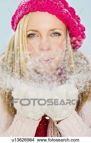 Picture - Studio portrait of young woman blowing snow. Fotosearch