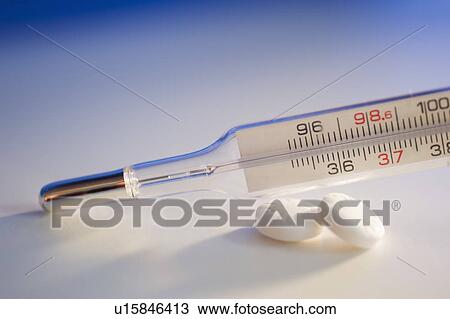 Stock Image - Thermometer and aspirin, close-up. Fotosearch