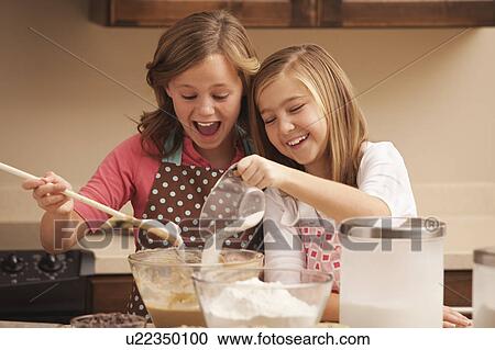 Stock Image - Two girls (10-11) baking in kitchen. Fotosearch