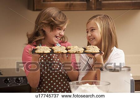 Two girls (10-11) holding biscuits in kitchen View Large Photo Image Stock Photo - Two girls (10-11) holding biscuits in kitchen. Fotosearch