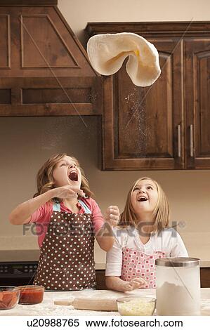 Two girls (10-11) tossing dough in kitchen View Large Photo Image Stock Photography - Two girls (10-11) tossing dough in kitchen. Fotosearch