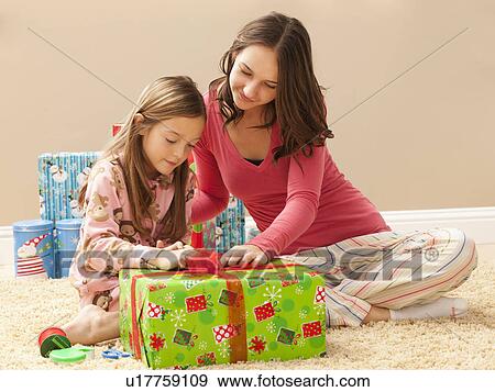 Stock Photo - Two sisters (6-7, 18-19) preparing Christmas presents. Fotosearch