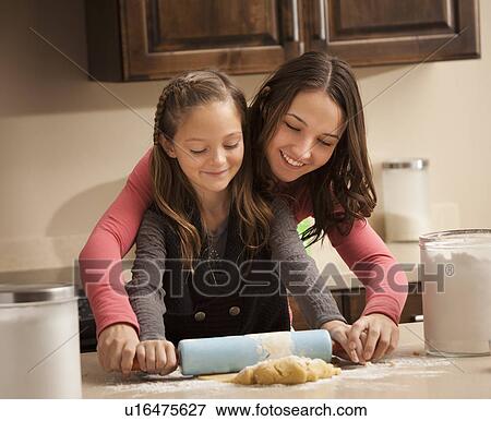 Two sisters (6-7, 18-19) rolling dough View Large Photo Image Stock Photo - Two sisters (6-7, 18-19) rolling dough. Fotosearch