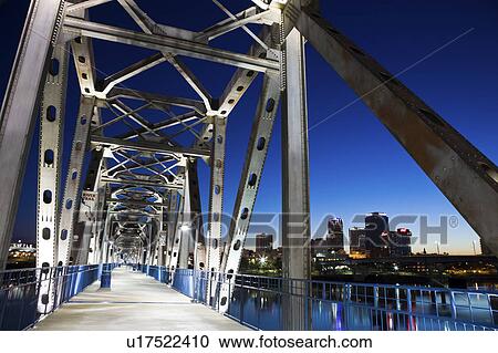 Stock Image - USA, Arkansas, Little Rock, Illuminated footbridge near downtown at night. Fotosearch