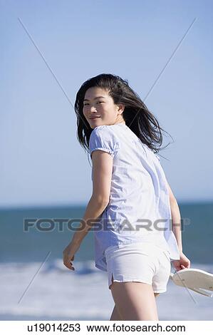 Stock Image - USA, California, Point Reyes, Young woman walking near sea. Fotosearch