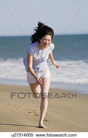 Stock Photography - USA, California, Point Reyes, Young woman running on beach. Fotosearch