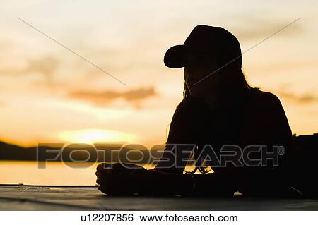 Stock Photograph - USA, California, Silhouette of young woman relaxing on beach at sunset. Fotosearch