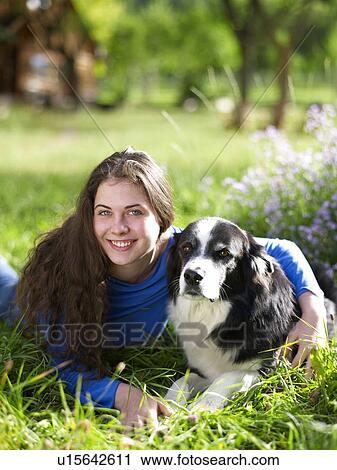 Stock Image - USA, Colorado, Portrait of young woman embracing dog on grass. Fotosearch