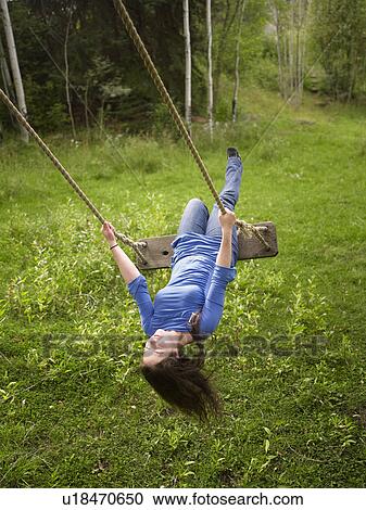 Stock Image - USA, Colorado, Young woman on swing in field. Fotosearch