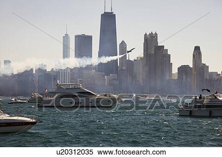 Stock Photography - USA, Illinois, Chicago, motor boats and airplane with cityscape at background. Fotosearch