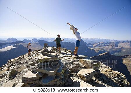 Stock Photo - USA, Montana, Glacier National Park, Hikers on the top of mountain. Fotosearch