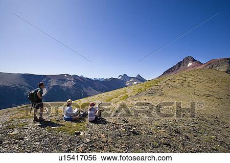 Stock Photograph - USA, Montana, Glacier National Park, Hikers resting on top. Fotosearch