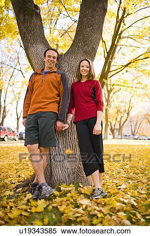 Stock Photography - USA, Montana, Kalispell, Happy couple standing and holding hands in autumn. Fotosearch