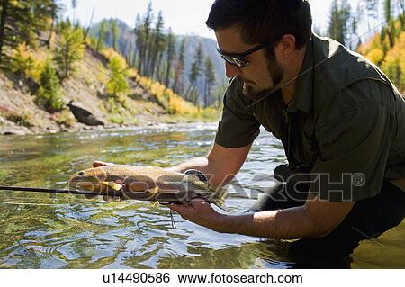 USA, Montana, Man holding fish in North Fork of Blackfoot River View Large Photo Image Stock Photograph - USA, Montana, Man holding fish in North Fork of Blackfoot River. Fotosearch