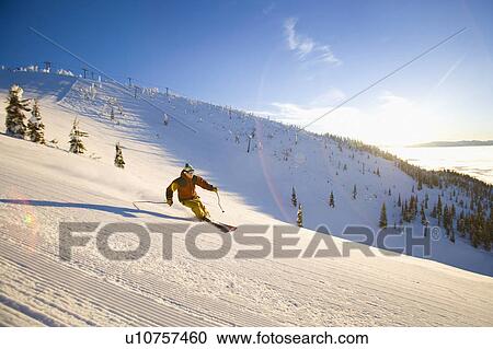 Stock Image - USA, Montana, Whitefish, Male skier on mountain slope at sunrise. Fotosearch