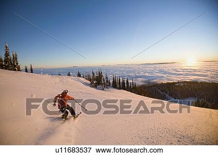Stock Photo - USA, Montana, Whitefish, Mid adult man skiing. Fotosearch
