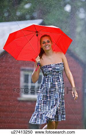 Stock Image - USA, Montana, Whitefish, Portrait of young woman with umbrella in rain . Fotosearch