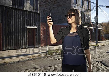 Stock Photograph - USA, New York City, Brooklyn, woman in street using phone. Fotosearch