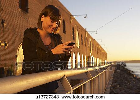 Stock Image - USA, New York City, Brooklyn, woman using cell phone. Fotosearch