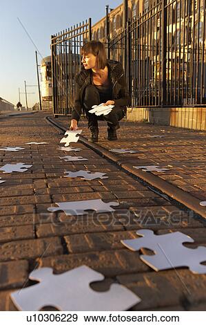Stock Photo - USA, New York City, Brooklyn, woman picking up jigsaw pieces from sidewalk. Fotosearch