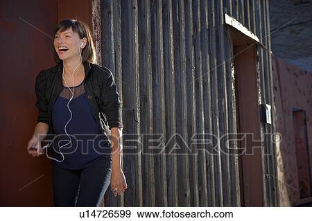 Stock Photo - USA, New York City, Brooklyn, woman listening to mp3 player. Fotosearch