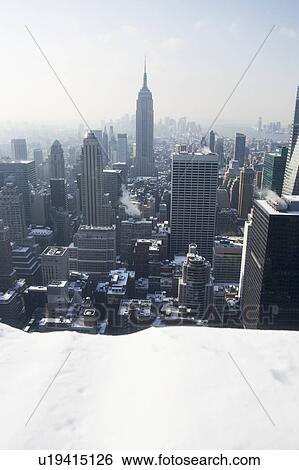 Stock Photograph - USA, New York City, View of Manhattan covered with snow, with Empire State Building in background. Fotosearch