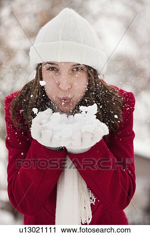 Stock Image - USA, Utah, Lehi, Portrait of young woman blowing snow. Fotosearch