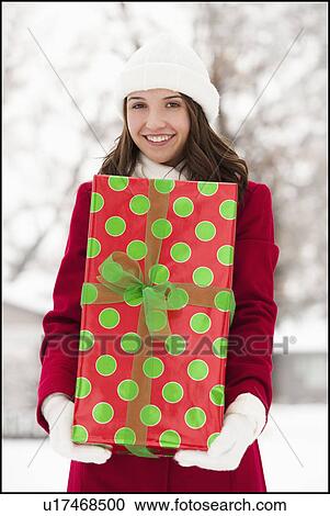 USA, Utah, Lehi, Portrait of young woman holding Christmas gift outdoors View Large Photo Image Stock Image - USA, Utah, Lehi, Portrait of young woman holding Christmas gift outdoors. Fotosearch