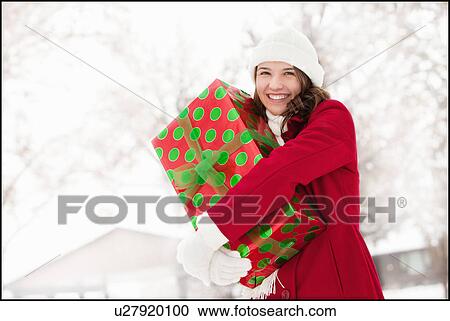 USA, Utah, Lehi, Portrait of young woman hugging Christmas gift outdoors View Large Photo Image Stock Image - USA, Utah, Lehi, Portrait of young woman hugging Christmas gift outdoors. Fotosearch