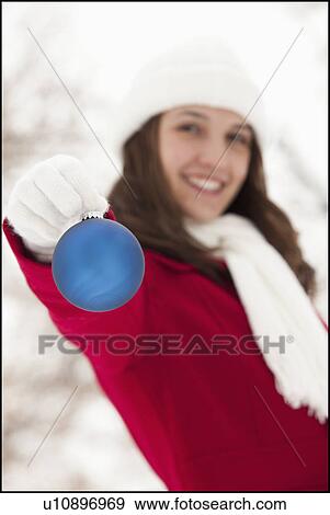 USA, Utah, Lehi, Portrait of young woman holding Christmas bauble outdoors View Large Photo Image Stock Photo - USA, Utah, Lehi, Portrait of young woman holding Christmas bauble outdoors. Fotosearch