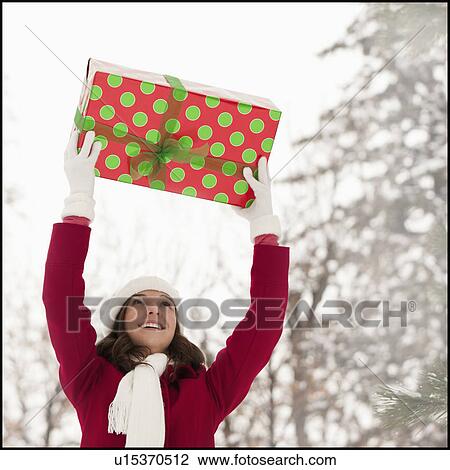 USA, Utah, Lehi, Young woman holding Christmas gift outdoors View Large Photo Image Stock Image - USA, Utah, Lehi, Young woman holding Christmas gift outdoors. Fotosearch
