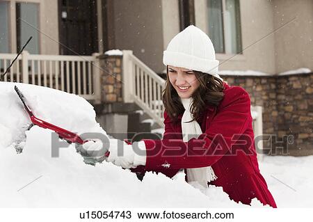 Stock Image - USA, Utah, Lehi, Young woman scraping snow from car. Fotosearch