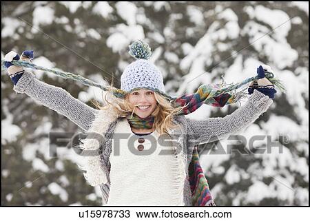 Stock Image - USA, Utah, Salt Lake City, portrait of young woman in winter clothing pulling hat strings. Fotosearch