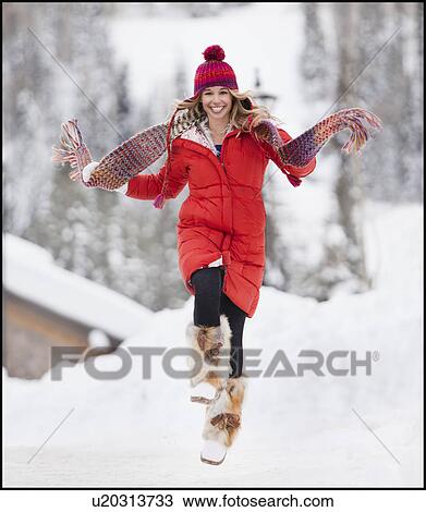 Stock Image - USA, Utah, Salt Lake City, Portrait of young woman skipping in snow. Fotosearch